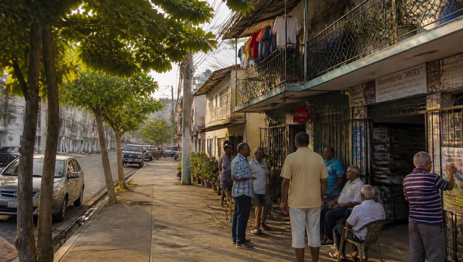 Neighborhood street in Panama City, with residents talking outside a corner shop in late afternoon light